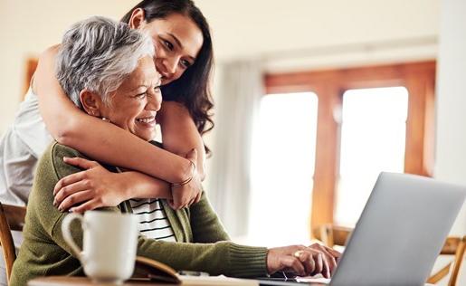 A woman hugging her mom in front of a laptop